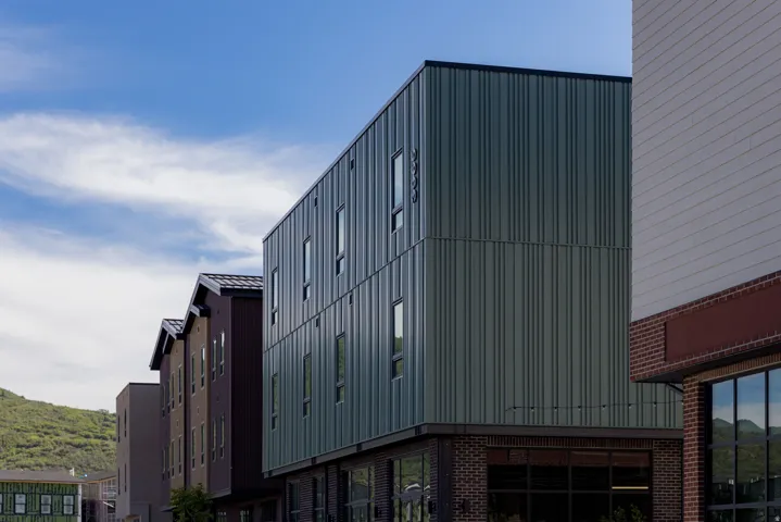 Modern multi-story building featuring vertical panel siding and a brick base