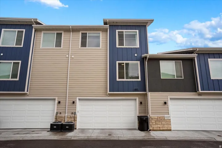 Contemporary townhome exterior featuring dual-tone siding, stone accents, two-car garage, and multiple windows