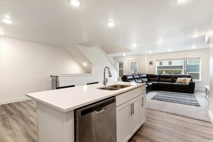 Kitchen island featuring a double-basin stainless steel sink, gooseneck faucet, and integrated dishwasher
