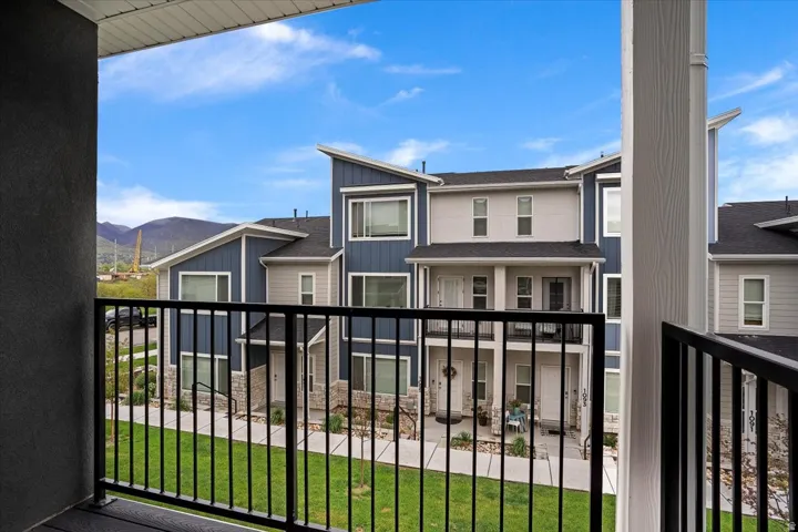 Exterior balcony with black metal railing overlooking a landscaped courtyard