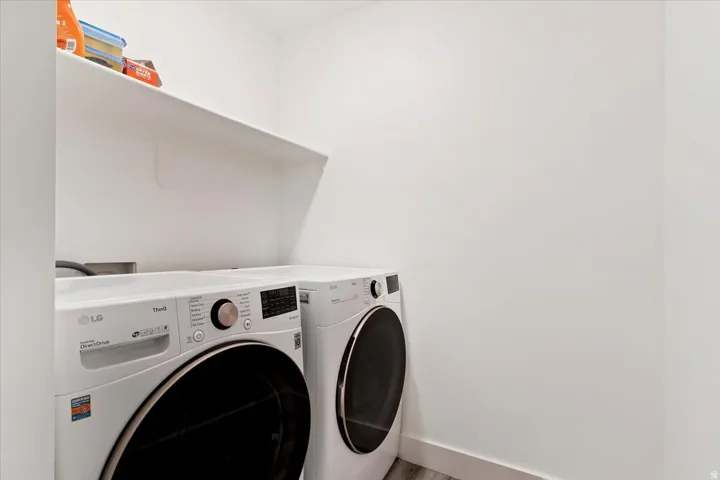 Laundry area featuring a built-in shelf, white walls, and wood-finish flooring