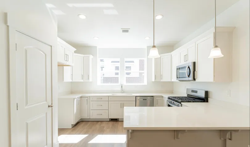 Modern kitchen featuring white shaker cabinetry, stainless steel appliances, light countertops, a subway tile backsplash, and wood-finish flooring