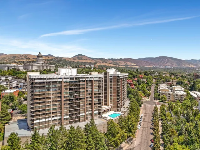 High-rise residential complex featuring a multi-story facade with balconies, an outdoor swimming pool, and mature tree-lined streets