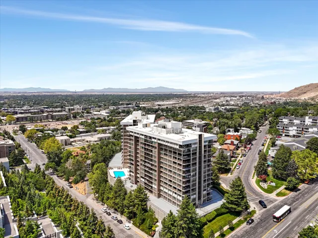 High-rise building featuring multiple levels of balconies, an outdoor swimming pool, and surrounding mature landscaping