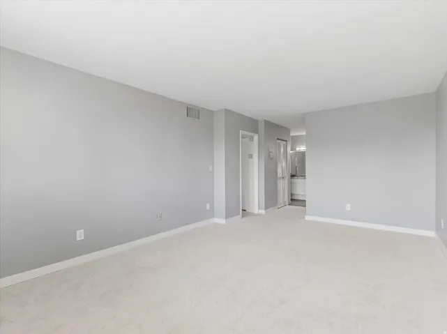 Spacious room with light gray walls and white baseboards