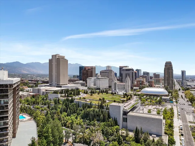 Expansive city skyline with prominent high-rise structures, featuring a distant mountain range backdrop