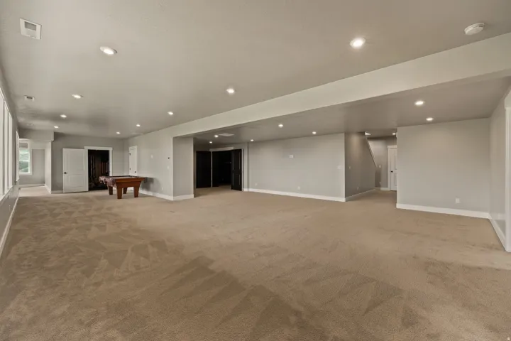 Expansive finished lower level featuring recessed lighting, light gray painted walls, and tan carpeting