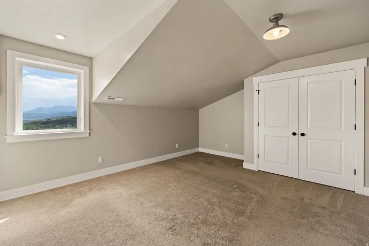 Carpeted room featuring a window with a mountain backdrop, a double-door closet with black hardware, recessed lighting, and a semi-flush mount ceiling fixture