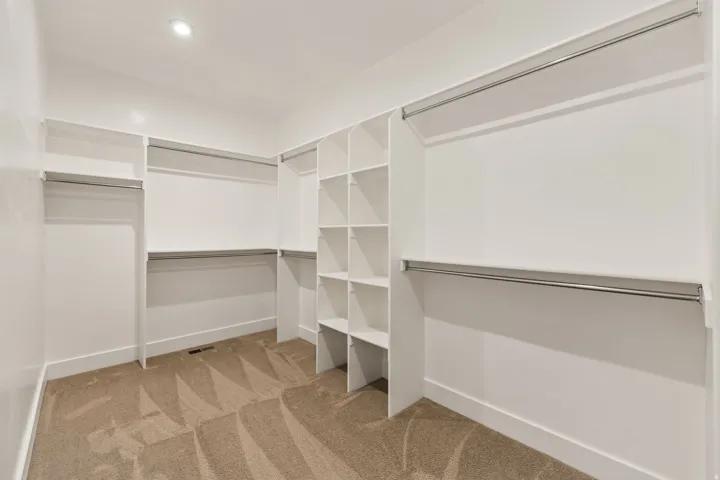 Spacious walk-in closet featuring built-in shelving, multiple hanging rods, and recessed lighting