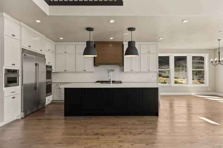 Contemporary kitchen featuring white cabinetry, a dark island with a light-colored countertop, and integrated stainless steel appliances