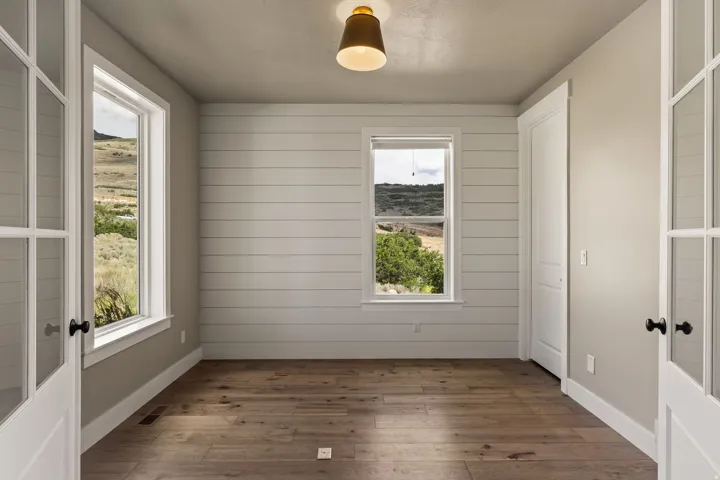 Interior space featuring wood-finish flooring, shiplap accent wall, white trim, and a contemporary ceiling light fixture
