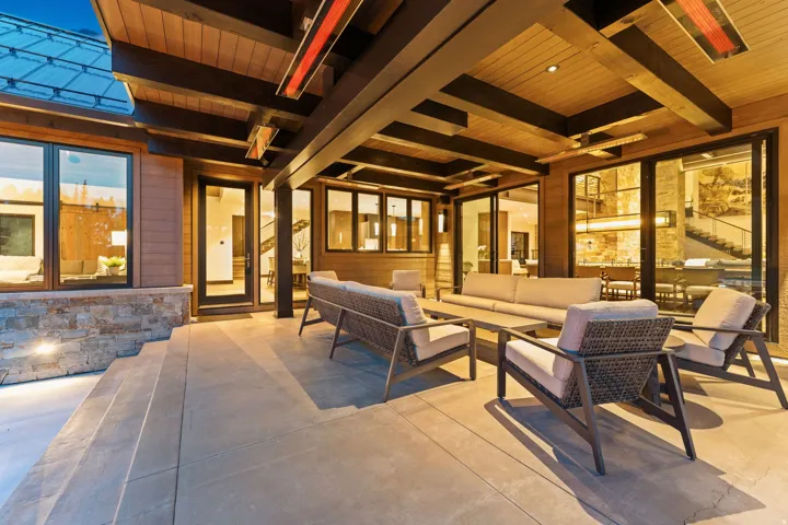 Expansive covered patio featuring a concrete surface, integrated lighting, and a wood-paneled ceiling with exposed beams