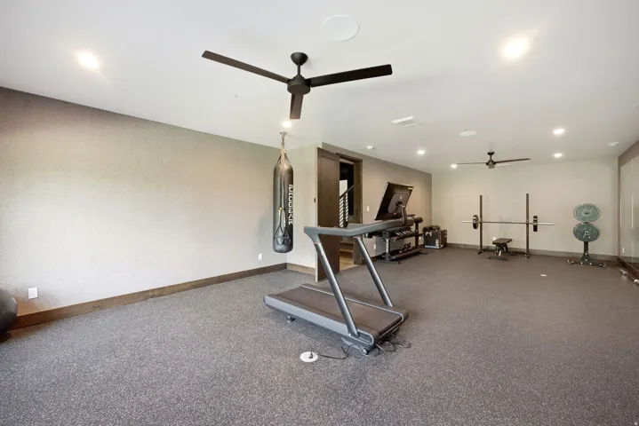 Spacious recreation room featuring recessed lighting, two ceiling fans, and durable speckled flooring