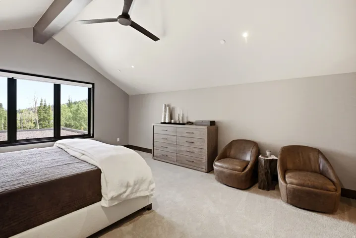 Vaulted ceilings with exposed beams and a modern ceiling fan define this space