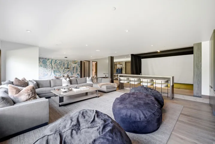 Expansive entertainment area featuring recessed lighting, light wood-finish flooring, and a large projection screen