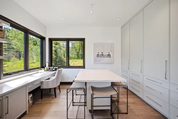 Dedicated workspace featuring expansive windows, built-in desk cabinetry, light wood-finish flooring, recessed lighting, and extensive built-in storage