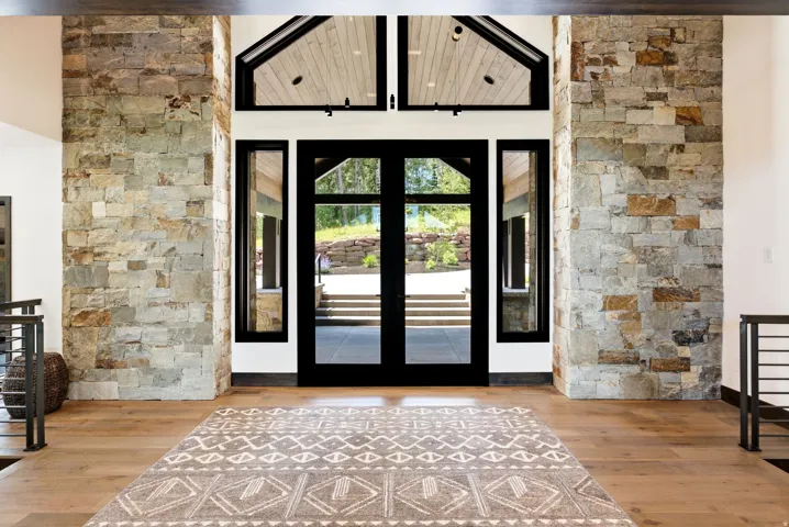 Grand entry featuring a double-door entrance with sidelights, transom windows, and a vaulted ceiling with wood paneling