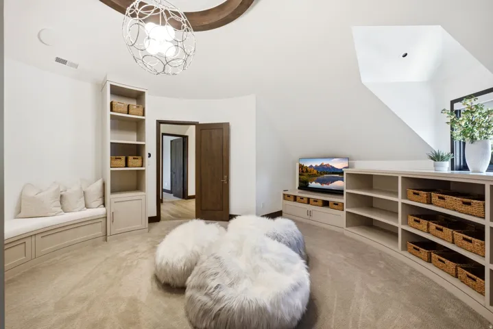 Curved wall features a long built-in shelving unit with open storage and integrated cabinetry