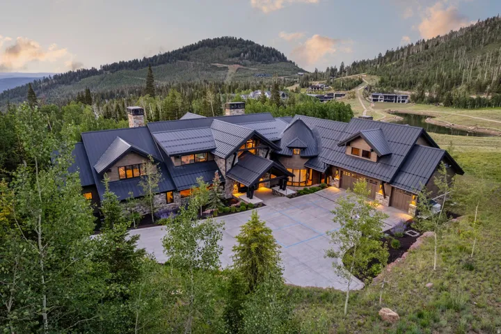 Expansive mountain property featuring a dark metal roof, stone and wood-panel exterior, multiple gables, and an integrated three-car garage