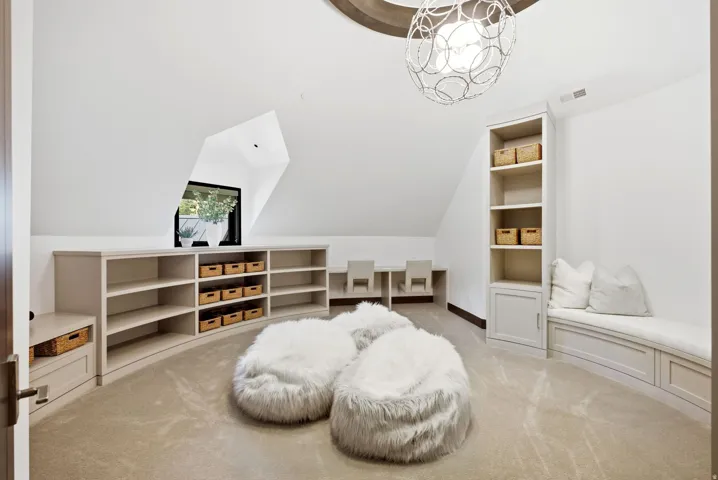 Spacious loft area featuring custom built-in shelving, an arched window, and recessed workspaces