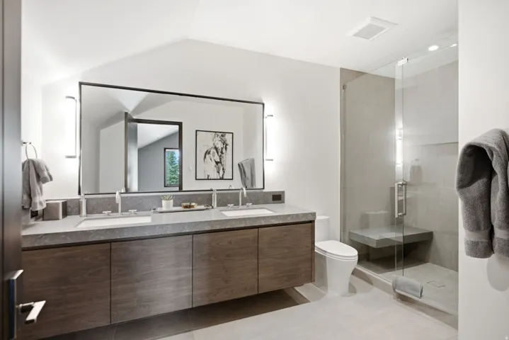 Contemporary bathroom featuring a floating dual vanity with a gray stone countertop, integrated sinks, and chrome faucets
