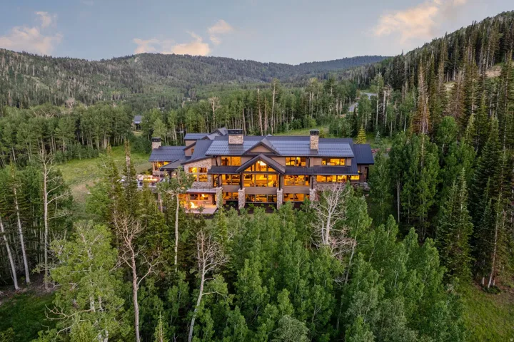 Expansive mountain property featuring a multi-level structure with stone and wood siding, multiple chimneys, and a dark-toned roof