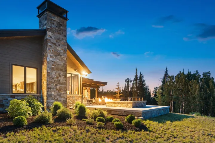 Stone-clad exterior featuring a prominent chimney, wood siding, and large windows