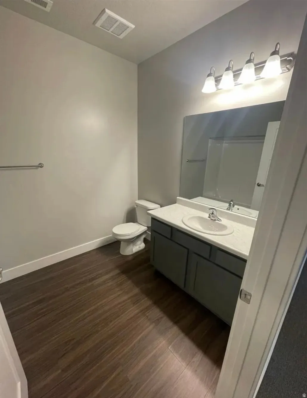 Vanity with integrated sink and chrome faucet, large mirror, and four-light fixture