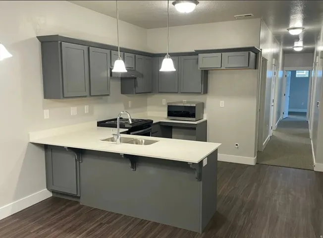 Modern kitchen featuring matte grey cabinetry, light-toned countertops, and two pendant lights over the island
