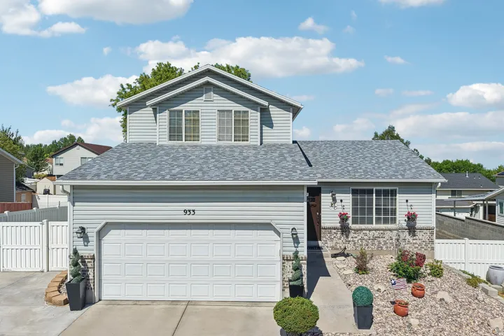 Light blue siding exterior featuring a multi-pane window, stone accent detailing, and a two-car garage