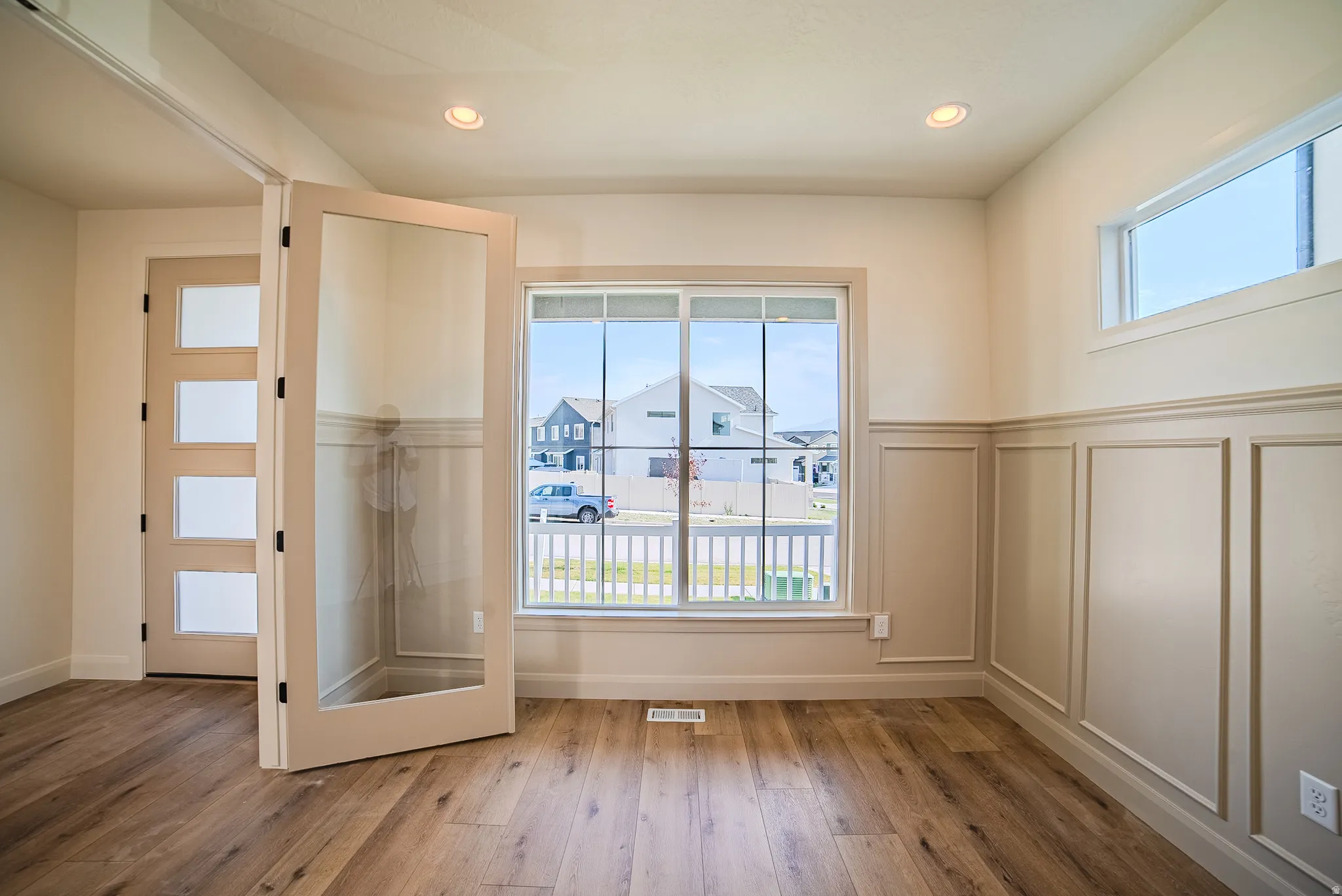 Room featuring wood-finish flooring, wainscoting with decorative trim, and recessed ceiling lights
