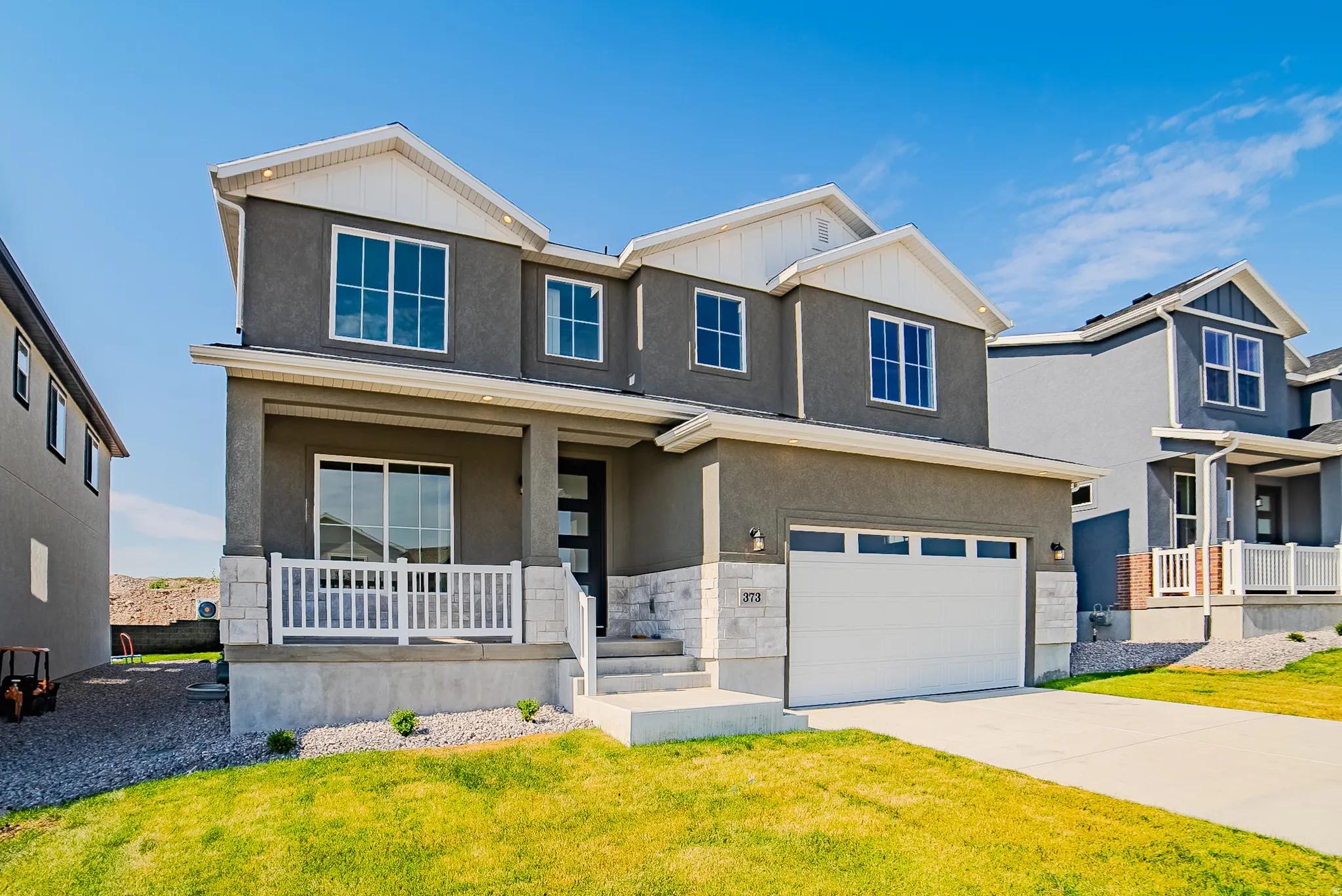 Contemporary two-story residence featuring a front-facing attached garage and a covered porch with white railing