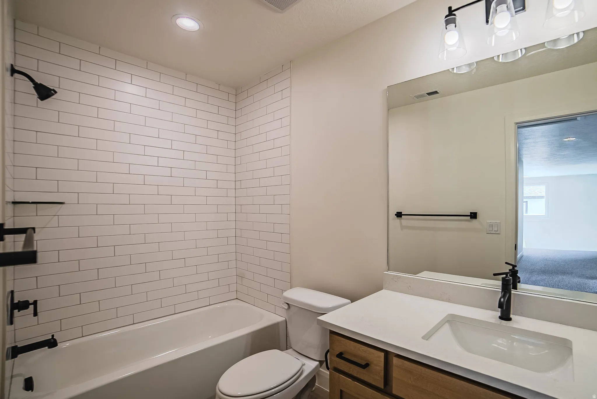 Bathroom featuring a subway-tiled tub and shower combination with matte black fixtures