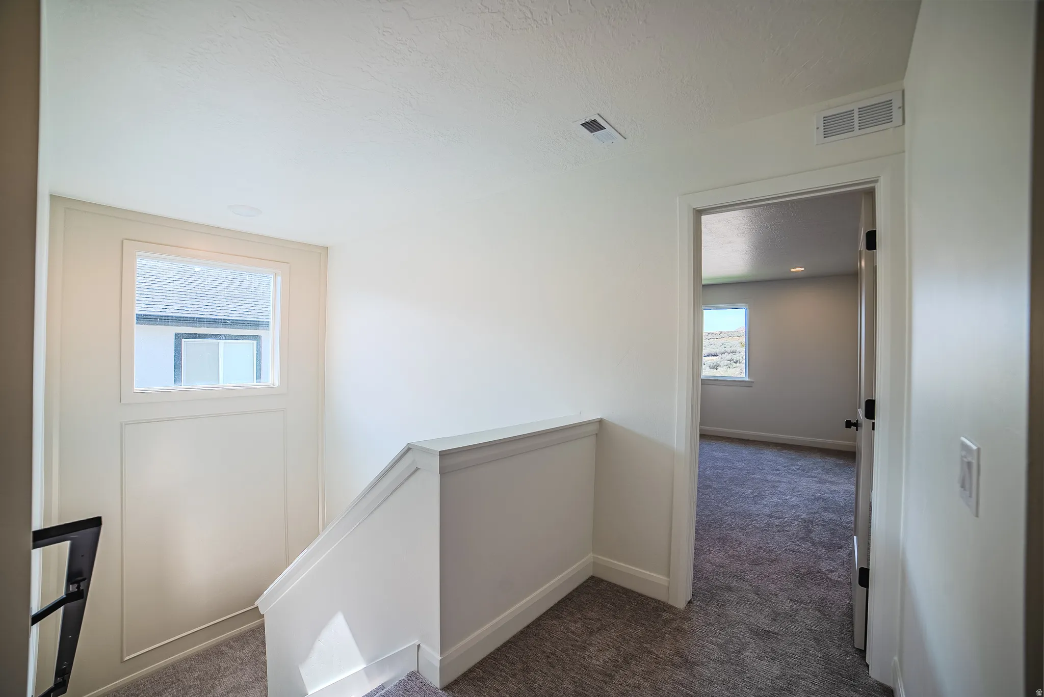 Upper-level landing featuring a window, painted white trim, white baseboards, and plush grey carpeting