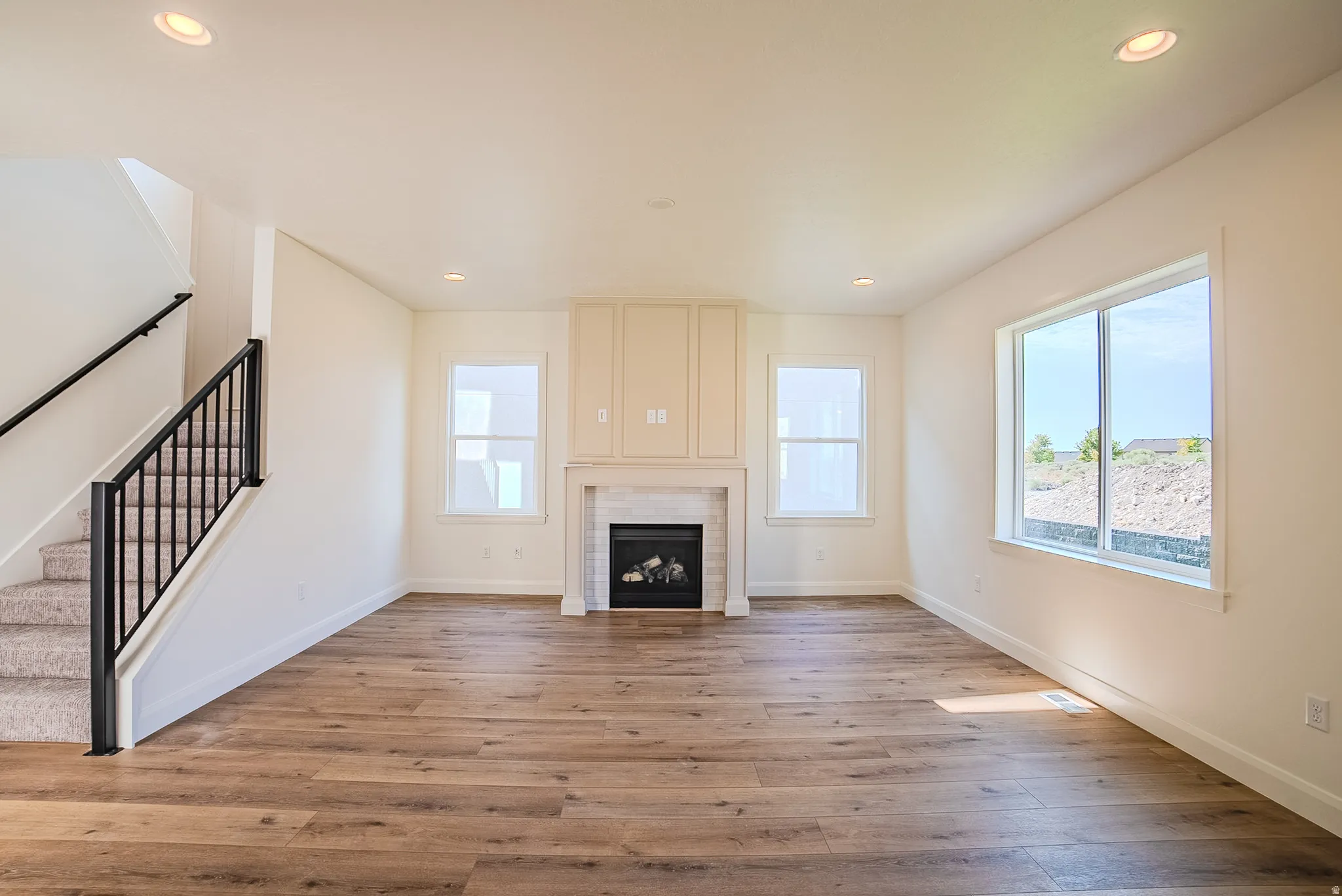 Spacious living area featuring wood-finish flooring, a fireplace with a tile surround and mantel, and built-in cabinetry