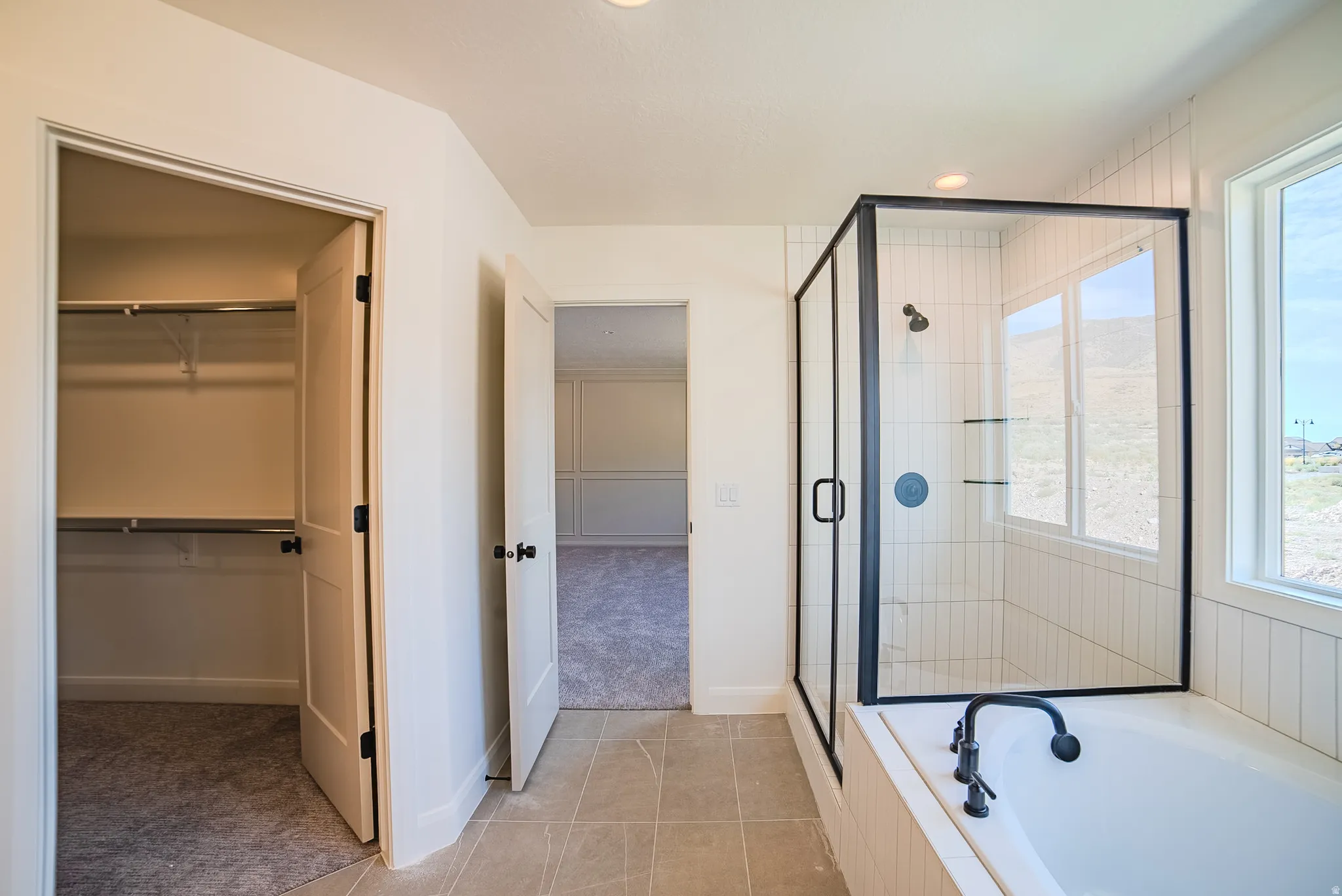 Enclosed glass shower with matte black fixtures and vertical white tile surround