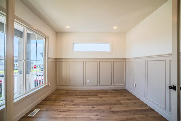 Room featuring wood-finish flooring, wainscoting paneling, recessed lighting, and a transom window