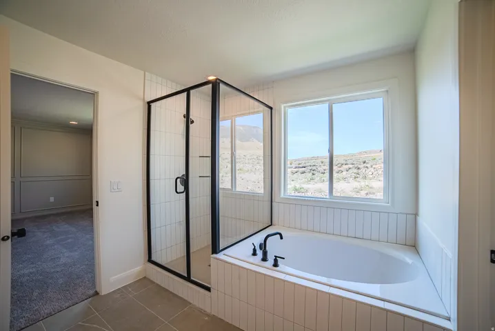 Contemporary bathroom featuring a freestanding tub, separate glass-enclosed shower with black framing, and a window with a mountain backdrop