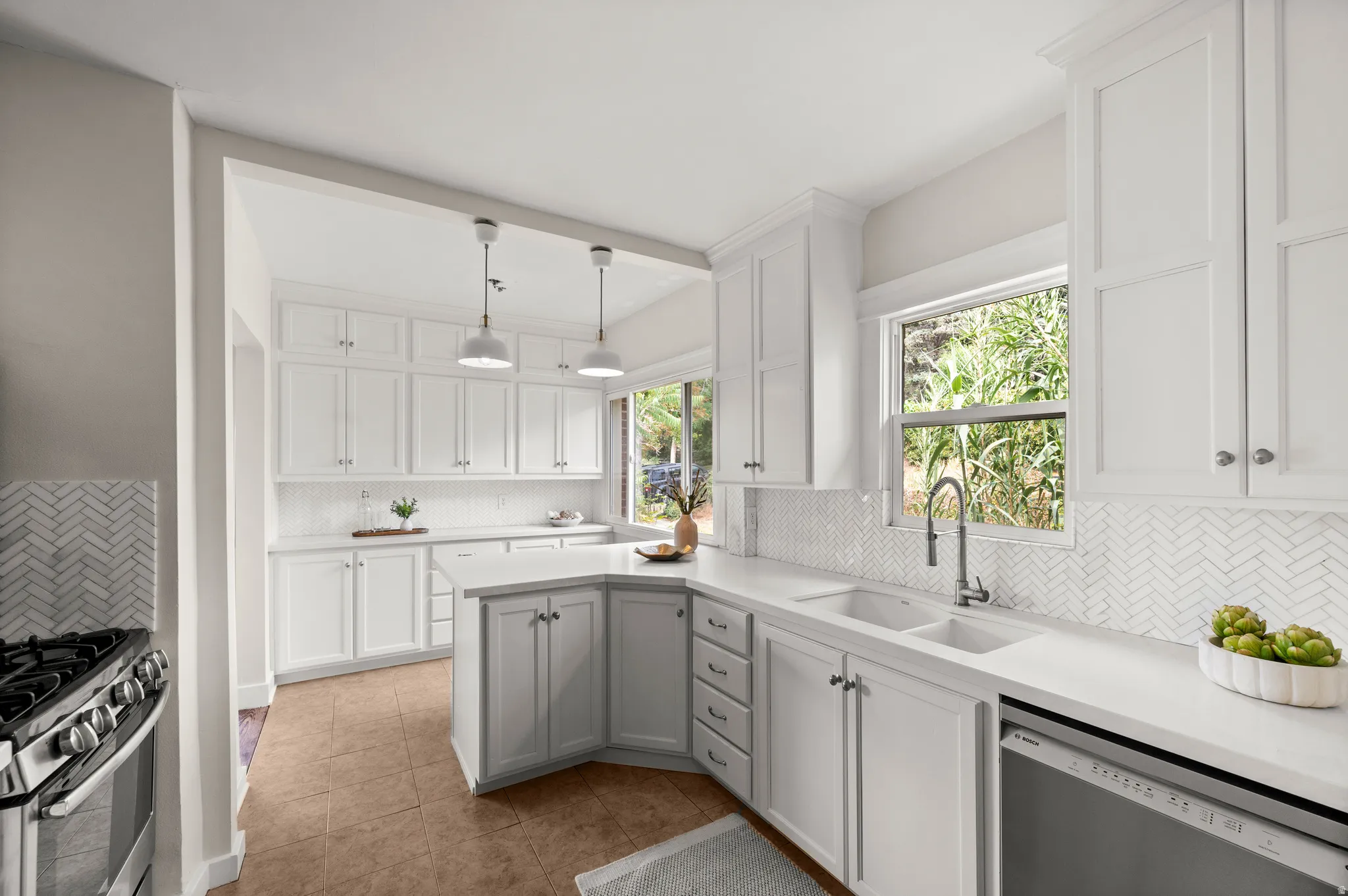 Kitchen featuring white shaker-style cabinetry, white countertops, white herringbone tile backsplash, a stainless steel gas range, and a stainless steel dishwasher