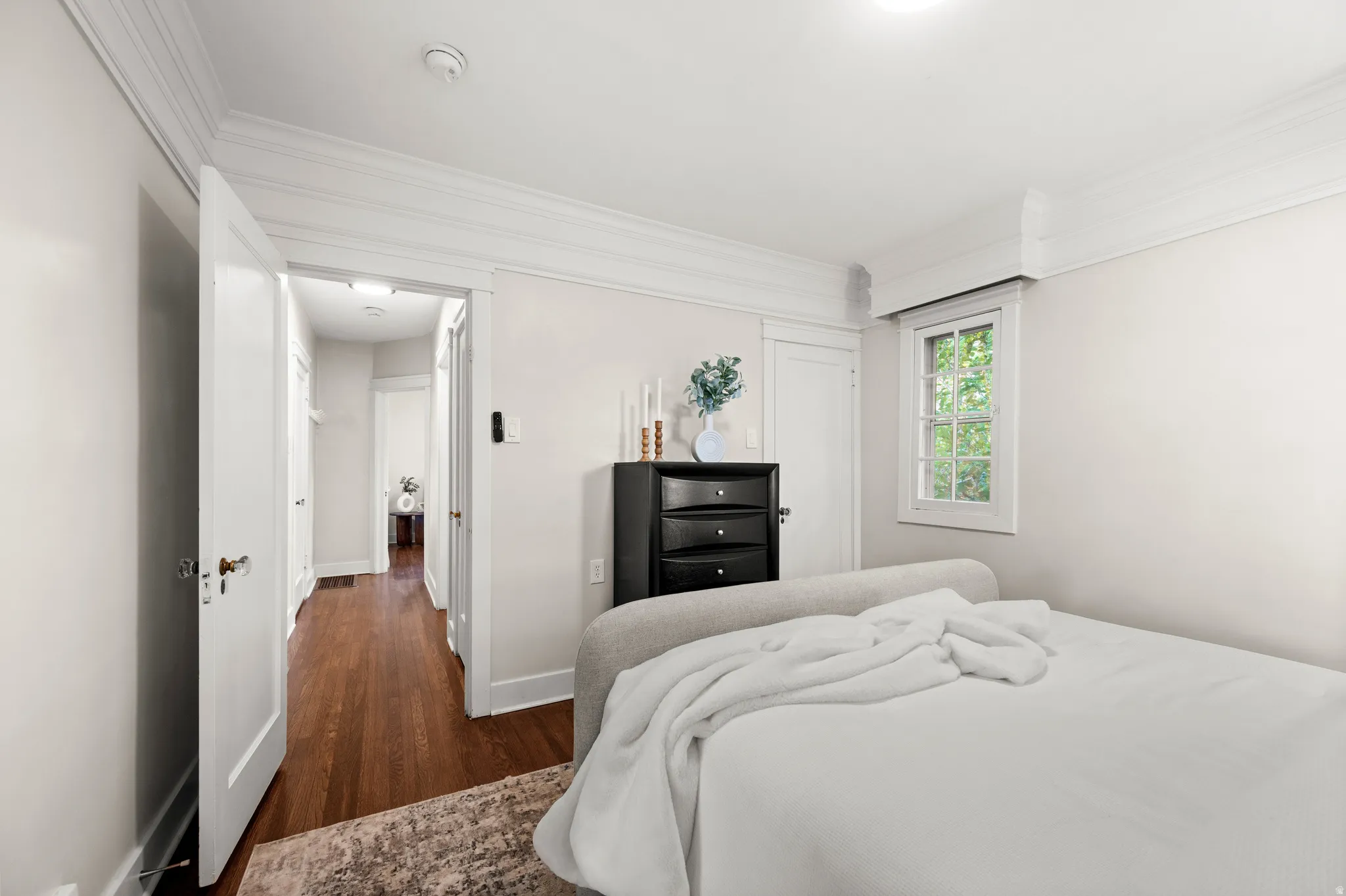 Room featuring wood-finish flooring, crisp white walls, and elegant crown molding