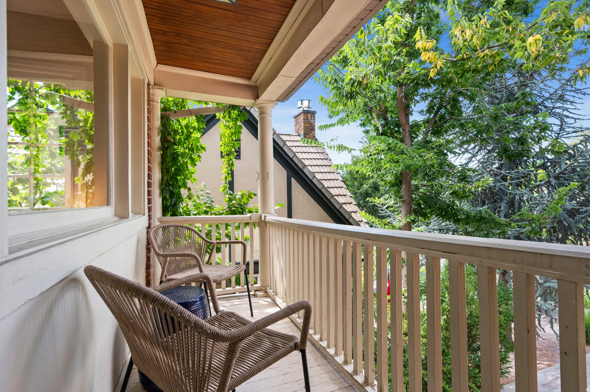 Covered porch featuring a wood-panel ceiling, white baluster railing, and a window with white trim