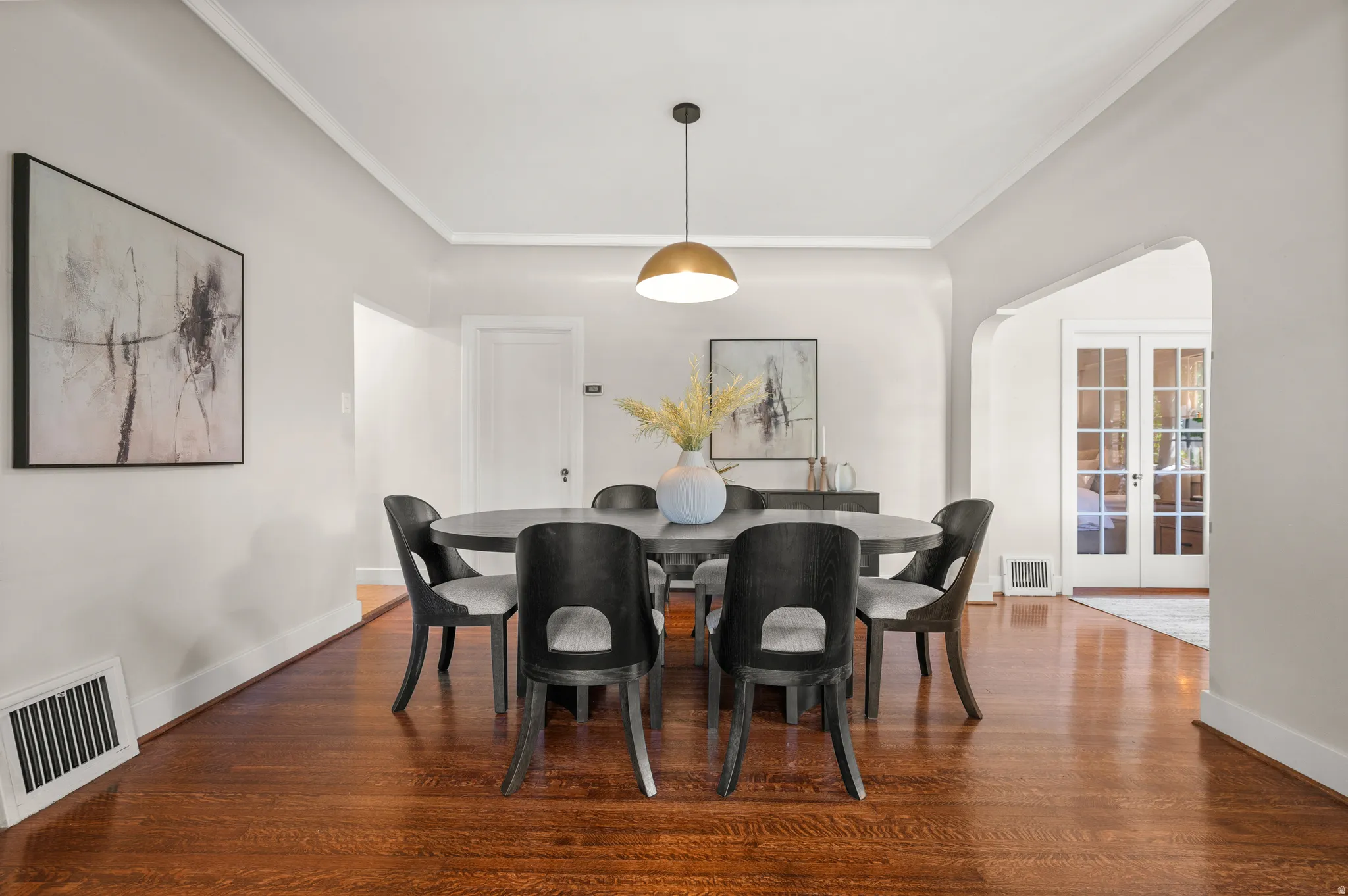 Hardwood flooring throughout, crown molding, and a brass-finish pendant light fixture