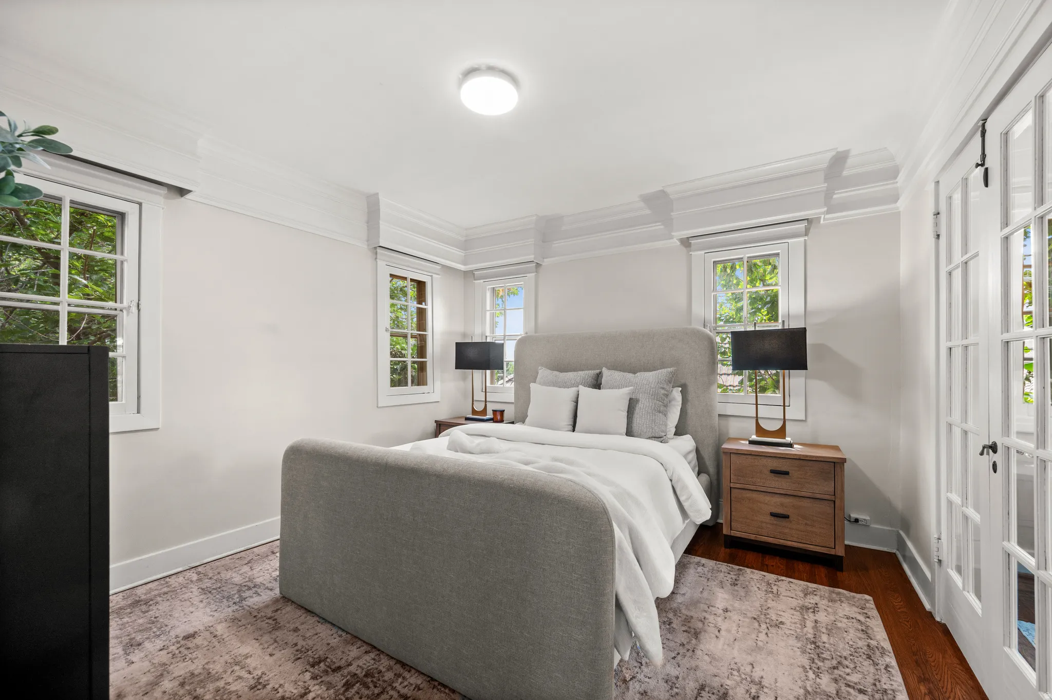 Bedroom featuring crown molding, hardwood flooring, multiple windows, and French doors