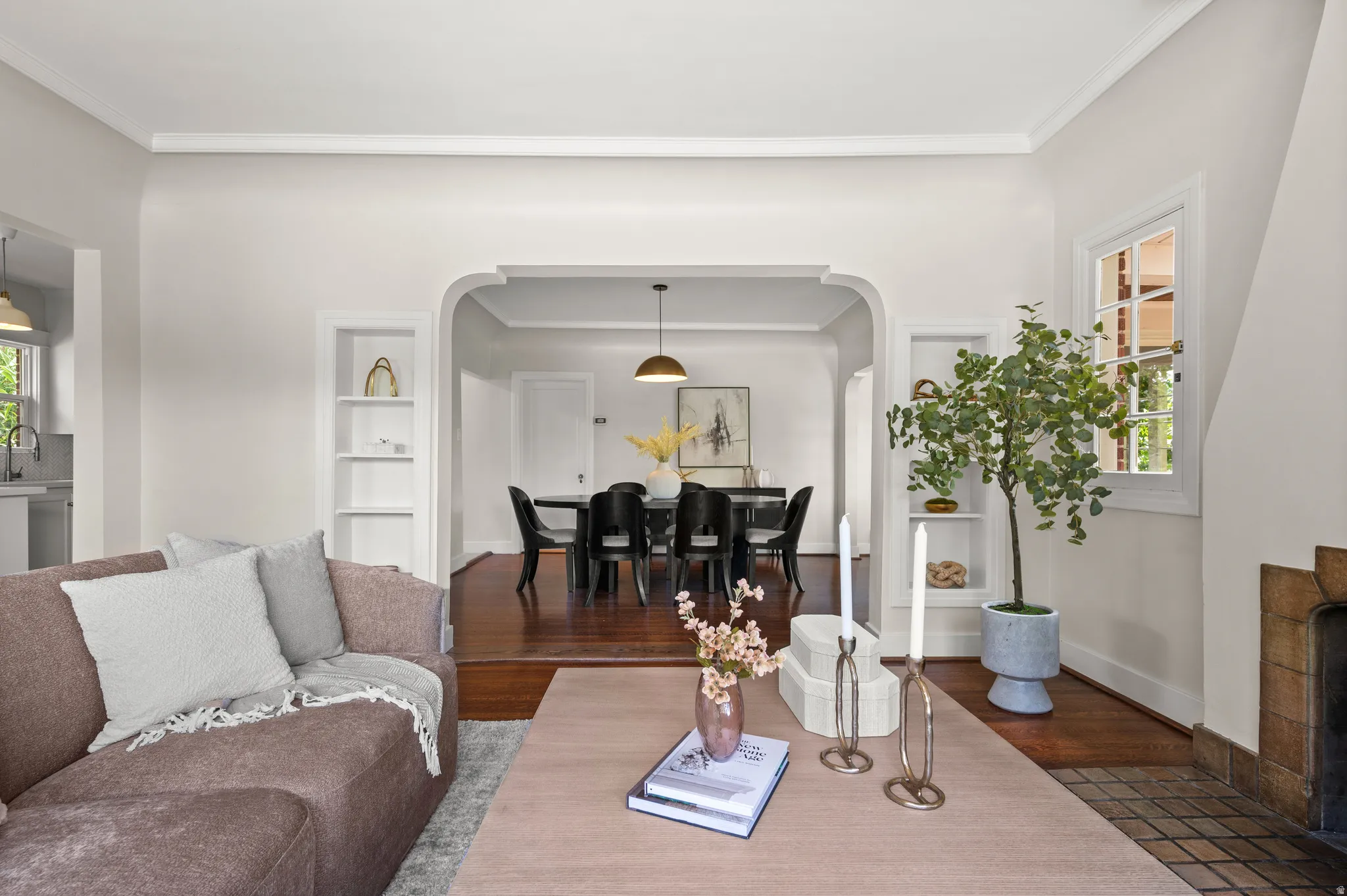 Living area featuring an arched doorway, built-in shelving, wood-finish flooring, and a window with natural light
