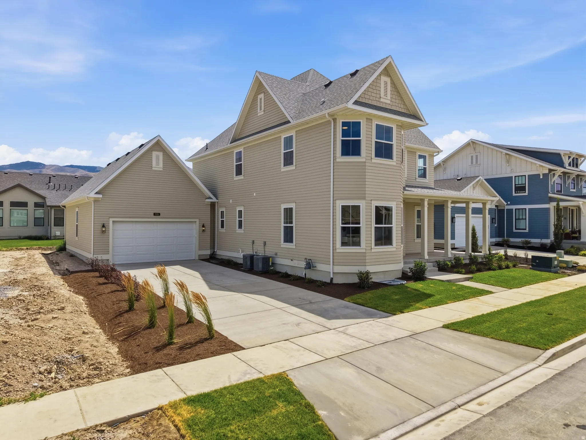 Two-story residence featuring light-colored siding, a covered front porch, and a detached two-car garage with an extended concrete driveway