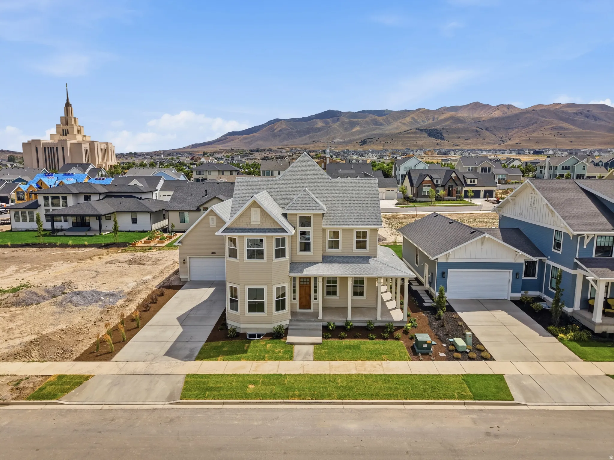 Contemporary residence featuring a covered front porch, bay windows, and a two-car garage