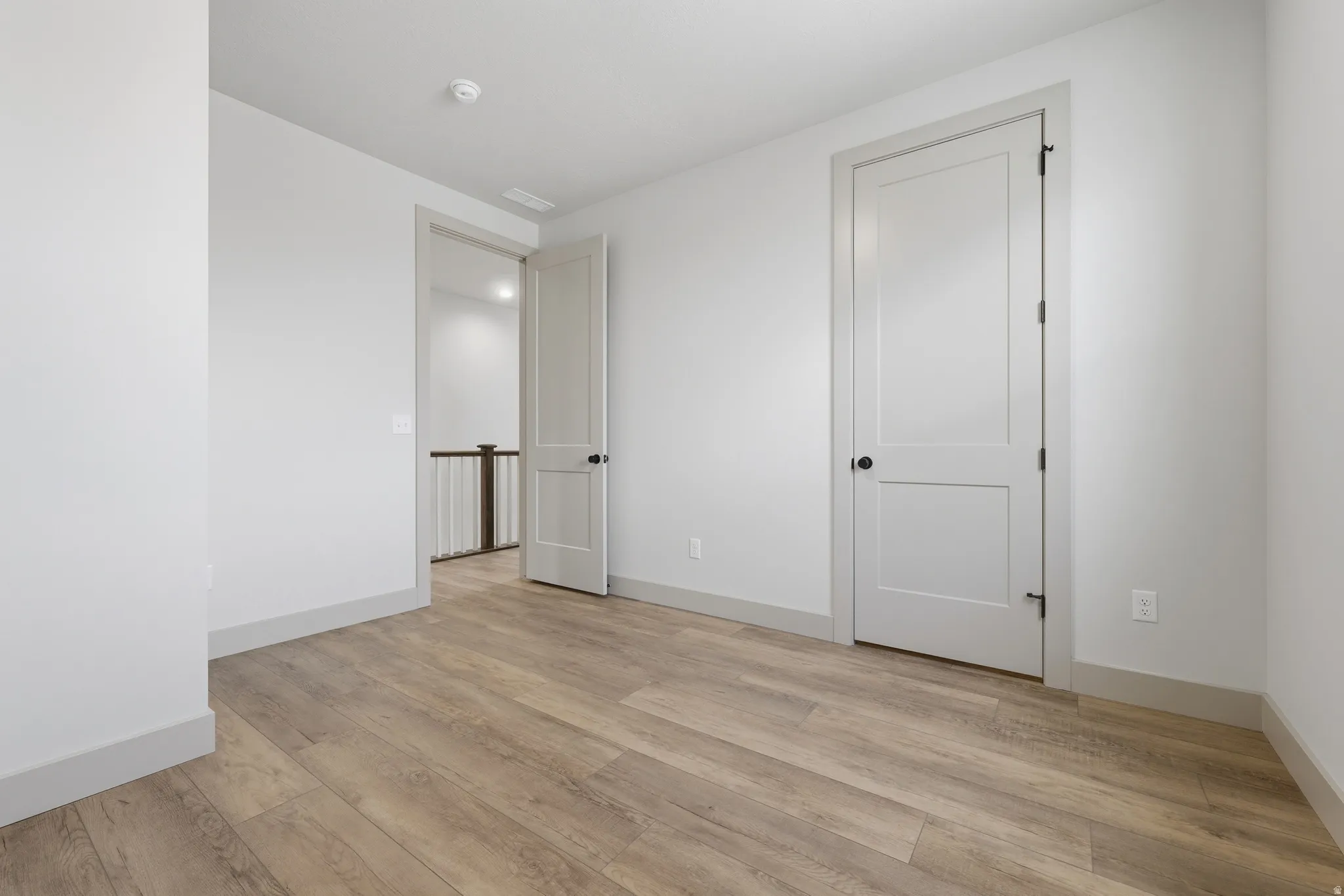 Neutral-toned room featuring wood-finish flooring, white walls, and white trim