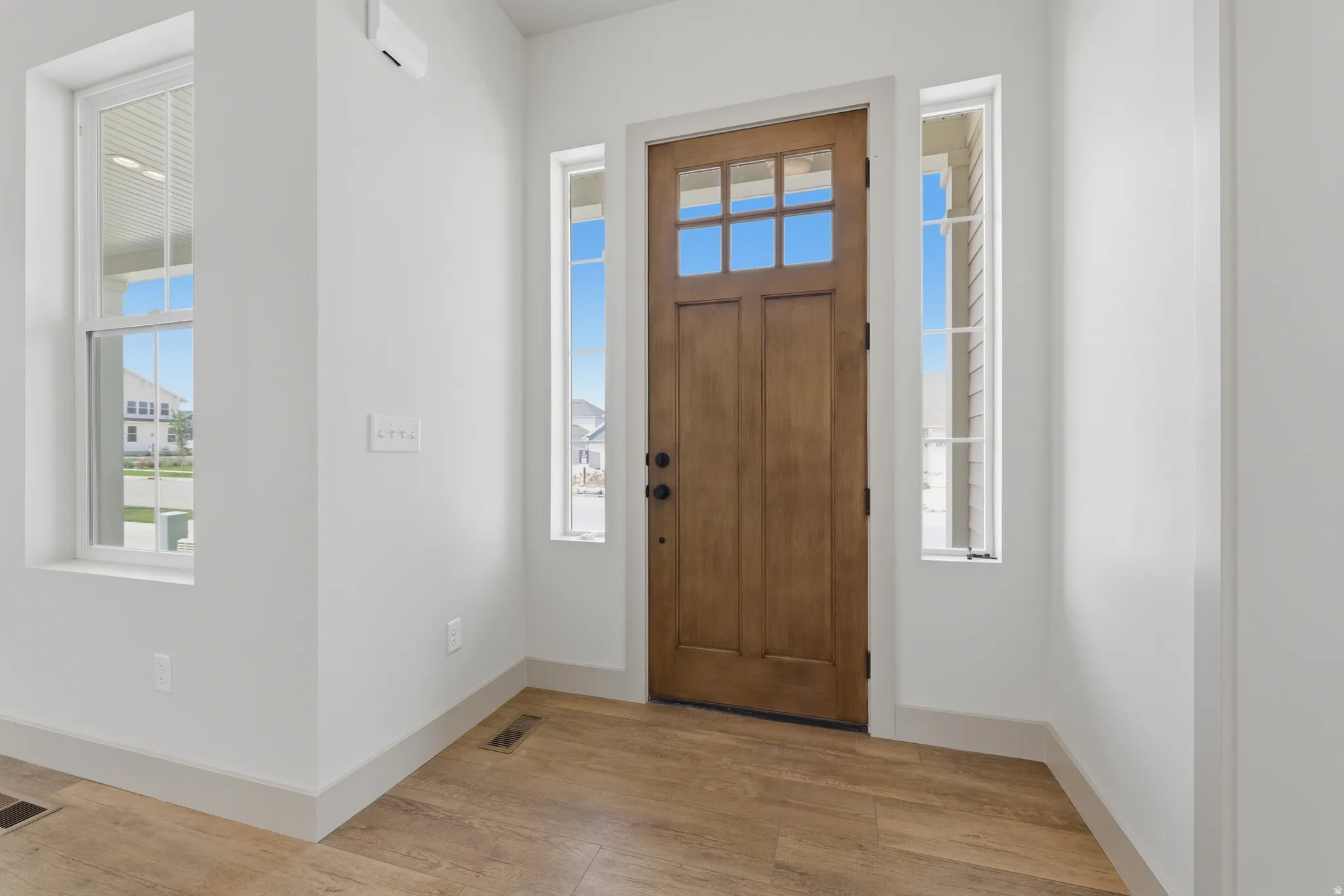 Wood-finish flooring welcomes at the entry, featuring a paneled front door with upper lites