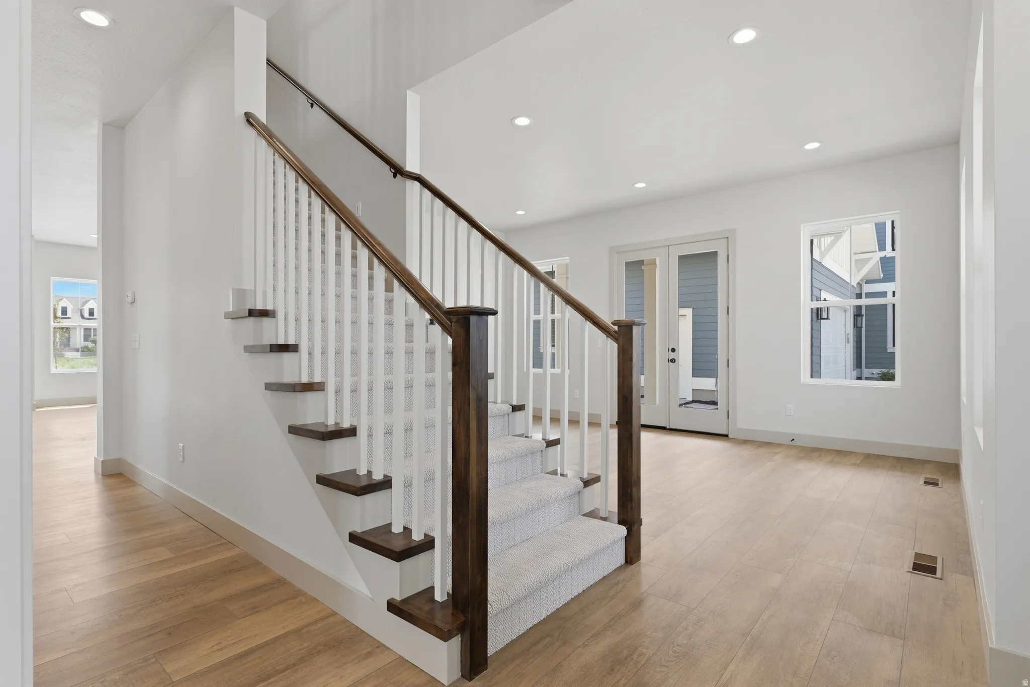 Staircase featuring dark wood newel posts and handrails, white balusters, and carpeted treads