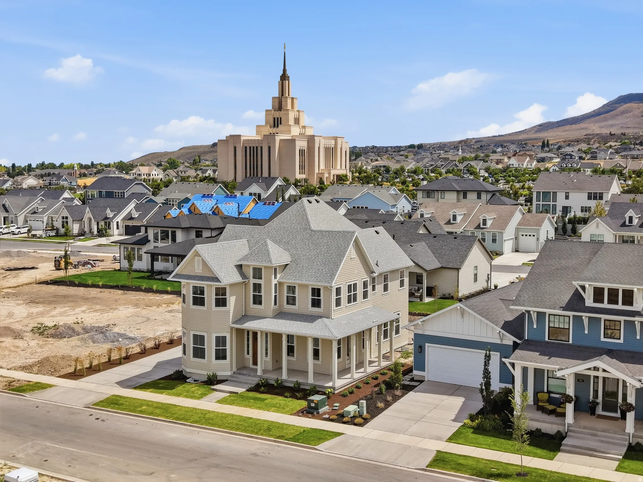 Newly constructed residence featuring a light beige exterior with white trim, a multi-gabled roof, and a covered front porch